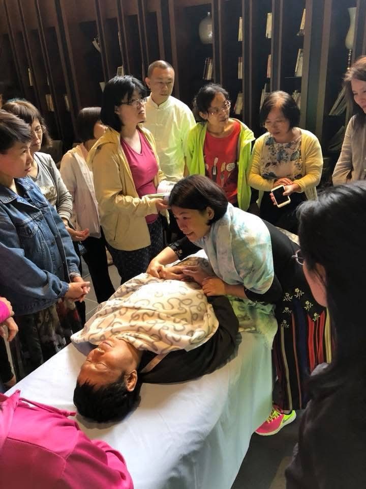 Alice老師在課堂中彎身示範仁神術手位,學員圍在一旁專注觀察